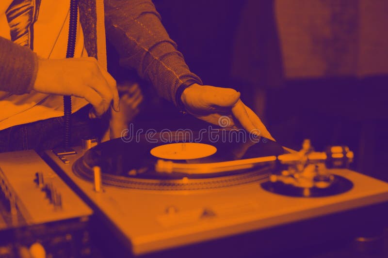 O DJ mistura trilhas no partido no jogador de registro do vinil foto de stock O DJ mistura trilhas no partido no jogador de registro do vinil foto de stock