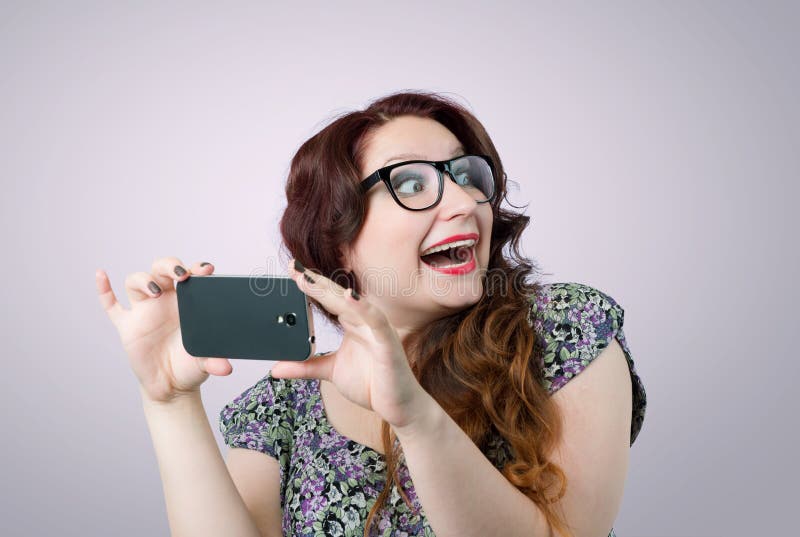 O doamnă amuzantă și fericită cu un smartphone royalty free stock photography