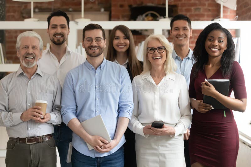 O echipă de afaceri fericită și diversă, care se află în birou și se uită la cameră stock image