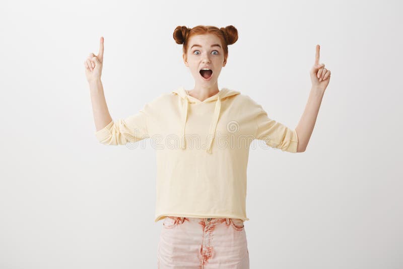 O espaço inacreditável da cópia está acima Estudante fêmea do ruivo atrativo emotivo com penteado de dois bolos na roupa na moda foto de stock royalty free O espaço inacreditável da cópia está acima Estudante fêmea do ruivo atrativo emotivo com penteado de dois bolos na roupa na moda foto de stock royalty free