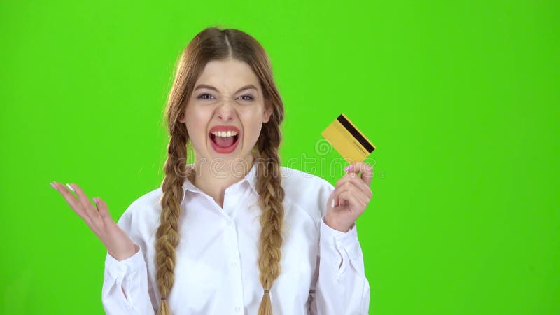 O estudante em uma blusa branca com um cartão de crédito está feliz Tela verde