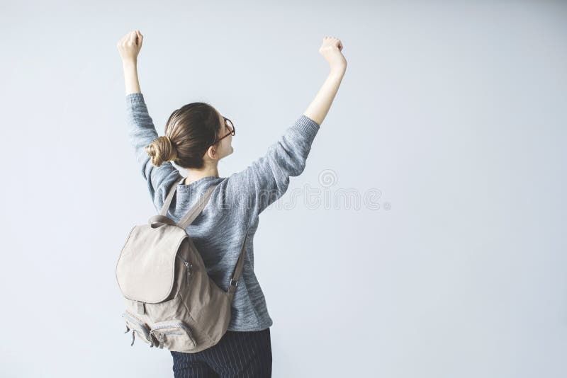 O estudante fêmea novo seguro aumentou acima os braços com trouxa fotos de stock royalty free O estudante fêmea novo seguro aumentou acima os braços com trouxa fotos de stock royalty free
