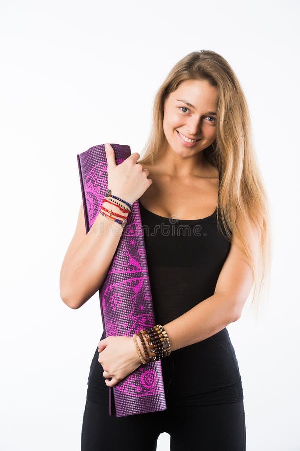 O estúdio disparou da mulher loura bonita nova que guardam a esteira da ioga e do levantamento pronto para o gym imagens de stock royalty free O estúdio disparou da mulher loura bonita nova que guardam a esteira da ioga e do levantamento pronto para o gym imagens de stock royalty free