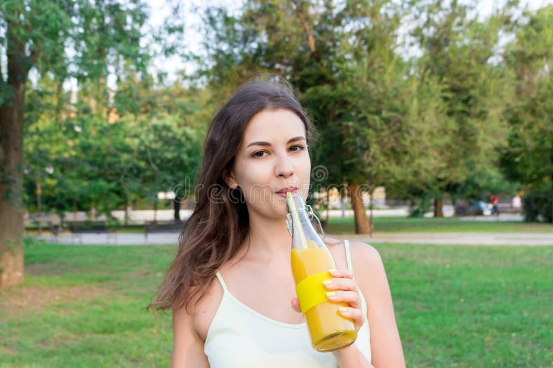 O fată frumoasă cu o sticlă de suc proaspăt. o femeie sănătoasă se dă cu limonada. nutriție Tulburări psihice stock photo