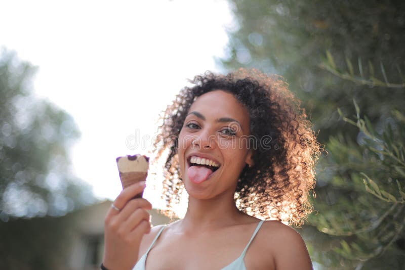 O femeie cu părul ondulat, cu o înghețată în mâini stock photos