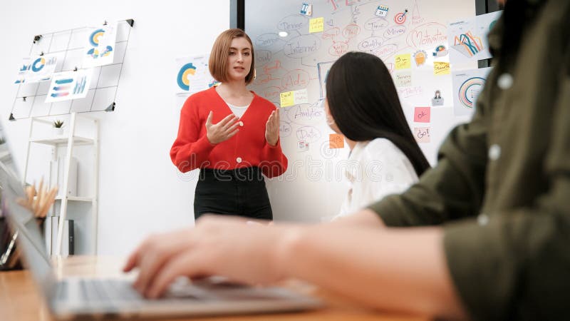 O femeie de afaceri prezintă o idee în timp ce investitorul lucrează folosind laptop. Imaculat stock image