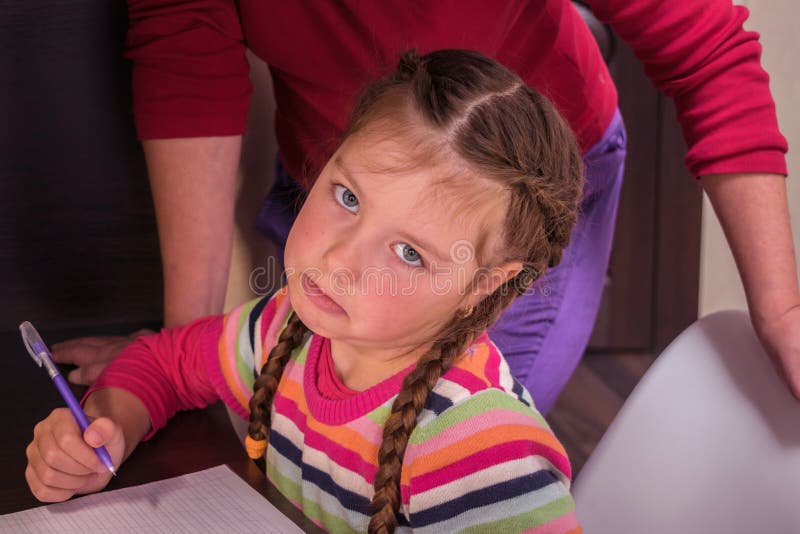 O fetiță nu vrea să învețe lecții. trist copil este obosit de teme școlare. mama o ajută pe fiica ei să-și facă temele. i cu royalty free stock photo
