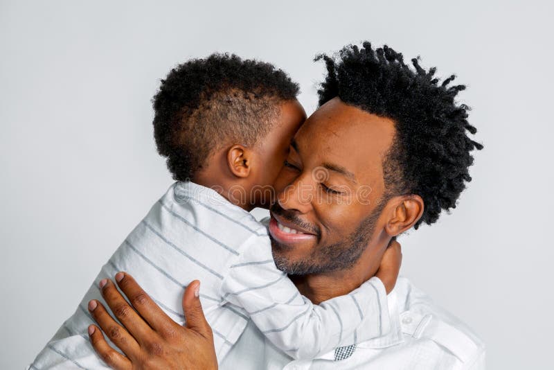 O filho afro-americano novo abraça seu pai