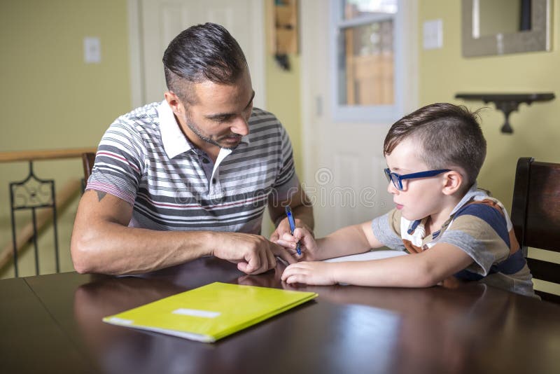 O filho de ajuda do pai faz trabalhos de casa O pai ajuda sua criança imagem de stock royalty free O filho de ajuda do pai faz trabalhos de casa O pai ajuda sua criança imagem de stock royalty free
