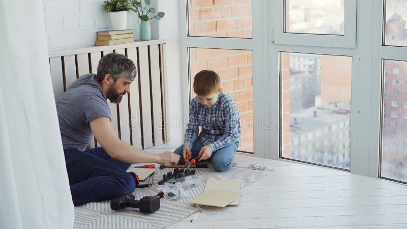 O filho pequeno de Urious e o pai loving são ocupados com a carpintaria que trabalha com instrumentos e que conduz pregos com mar