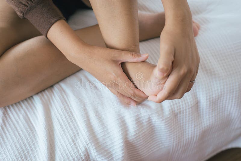 O fim acima da mulher que tem uma única dor do salto ou do pé, mãos da mulher que dão a massagem a ela paga no quarto fotografia de stock royalty free O fim acima da mulher que tem uma única dor do salto ou do pé, mãos da mulher que dão a massagem a ela paga no quarto fotografia de stock royalty free