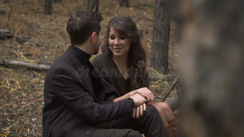 O fim acima de pares felizes está tendo uma data no homem de sorriso da floresta e a mulher está sentando no início de uma sessão