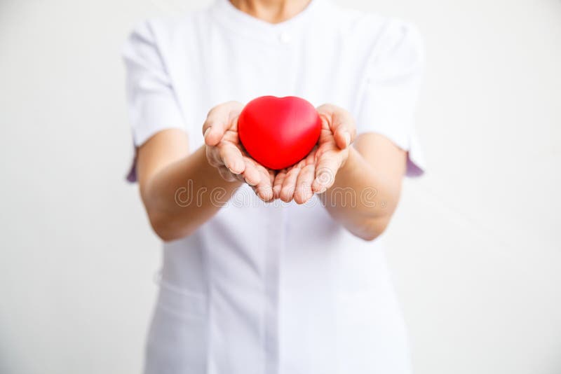 O foco seletivo do coração vermelho guardou pelo ` fêmea s da enfermeira ambo a mão, representando dando todo o esforço para entr