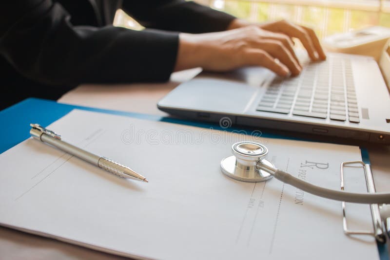 O funcionamento do doutor no laptop, clipbo da prescrição da escrita fotos de stock O funcionamento do doutor no laptop, clipbo da prescrição da escrita fotos de stock