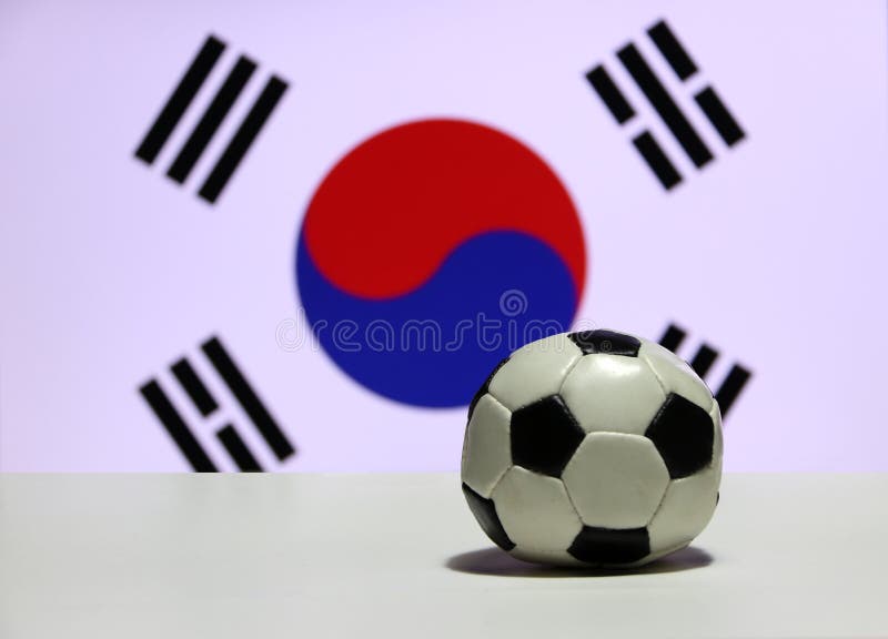 O futebol pequeno no assoalho branco com para fora focaliza Yin Yang vermelha e azul e quatro trigrams pretos da bandeira coreana foto de stock O futebol pequeno no assoalho branco com para fora focaliza Yin Yang vermelha e azul e quatro trigrams pretos da bandeira coreana foto de stock