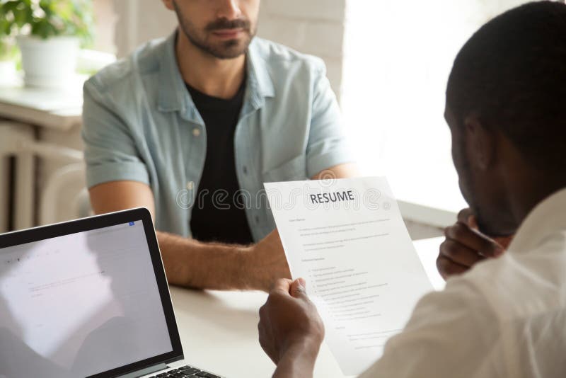 O gerente afro-americano da hora que guarda candidatos da leitura recomeça em fotos de stock royalty free O gerente afro-americano da hora que guarda candidatos da leitura recomeça em fotos de stock royalty free