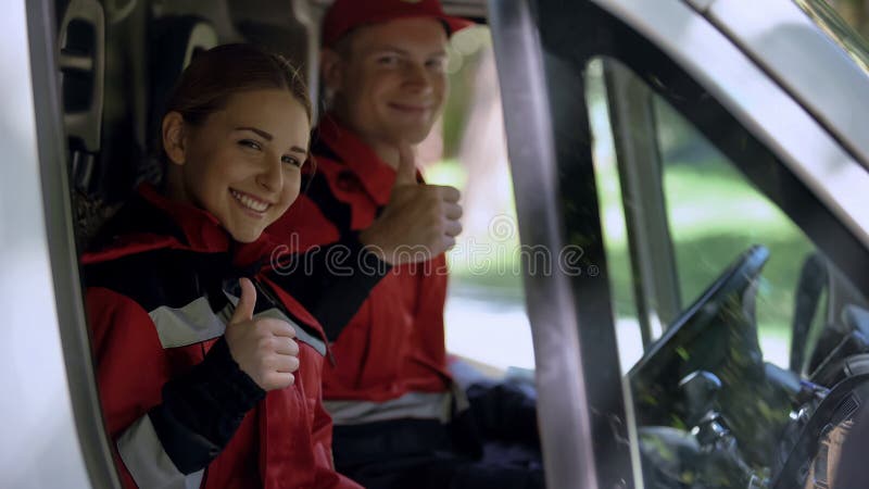 O grupo da ambulância que mostra os polegares acima, profissionais no dever fornece primeiros socorros imagem de stock royalty free O grupo da ambulância que mostra os polegares acima, profissionais no dever fornece primeiros socorros imagem de stock royalty free