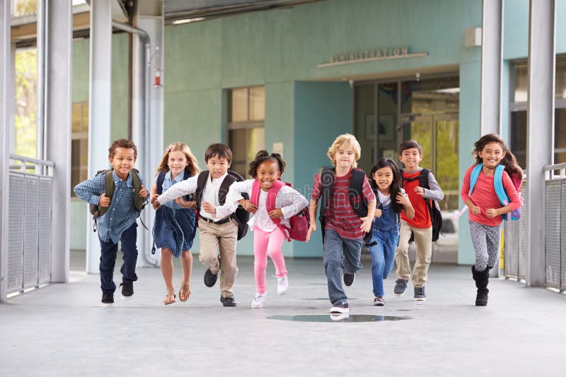 O grupo de escola primária caçoa o corredor em um corredor da escola