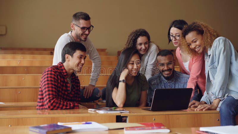 O grupo de estudantes está participando na videoconferência usando o portátil, estão olhando as mãos e a fala de ondulação da tel