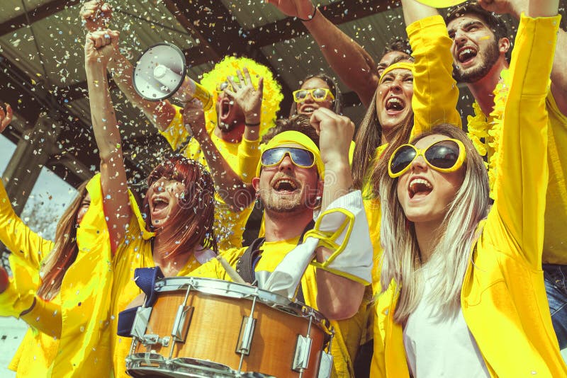 O grupo de fãs vestiu-se na cor amarela que olham um evento de esportes