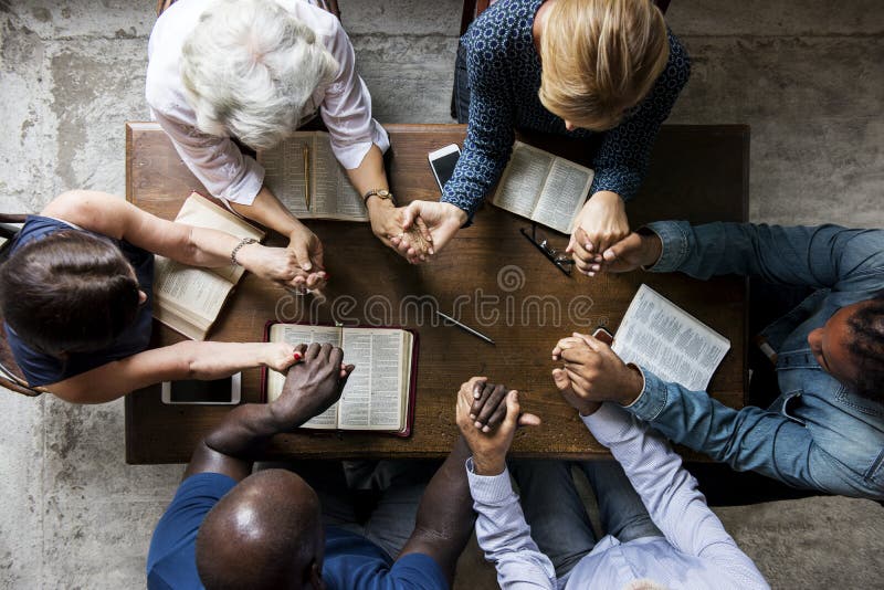 O grupo de pessoas que guarda as mãos que rezam a adoração acredita