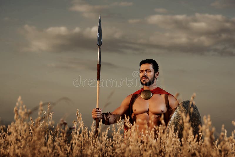 O guerreiro que vestem no casaco vermelho e a armadura gostam espartano fotografia de stock O guerreiro que vestem no casaco vermelho e a armadura gostam espartano fotografia de stock
