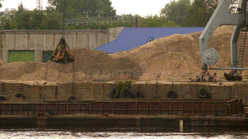 O guindaste da carga do porto extrai a areia do rio, produção