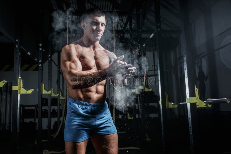 O halterofilista atlético do homem bombeado golpeia a magnésia no gym fotos de stock O halterofilista atlético do homem bombeado golpeia a magnésia no gym fotos de stock