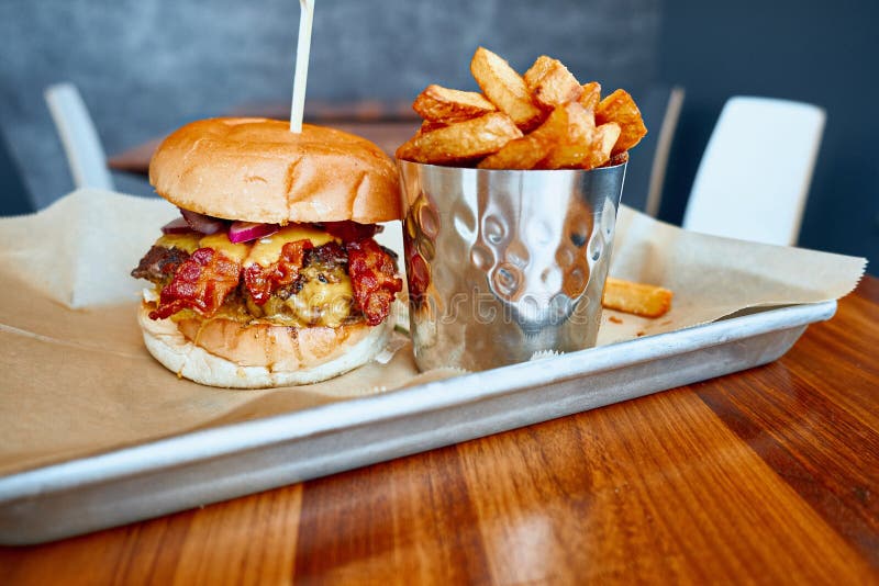 O hamburguer feito home suculento serviu com fritadas friáveis fotografia de stock O hamburguer feito home suculento serviu com fritadas friáveis fotografia de stock