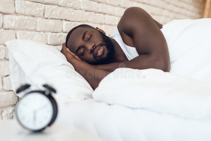 O homem afro-americano dorme na cama foto de stock royalty free O homem afro-americano dorme na cama foto de stock royalty free