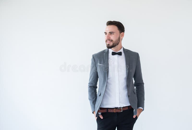 O homem caucasiano considerável com o farpado na posição formal do smoking e do terno e no sorriso no fundo branco, copia o espaç imagens de stock O homem caucasiano considerável com o farpado na posição formal do smoking e do terno e no sorriso no fundo branco, copia o espaç imagens de stock