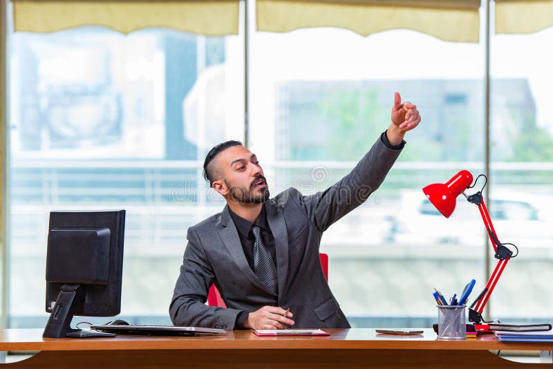 O homem com seus polegares acima na mesa de escritório fotos de stock O homem com seus polegares acima na mesa de escritório fotos de stock