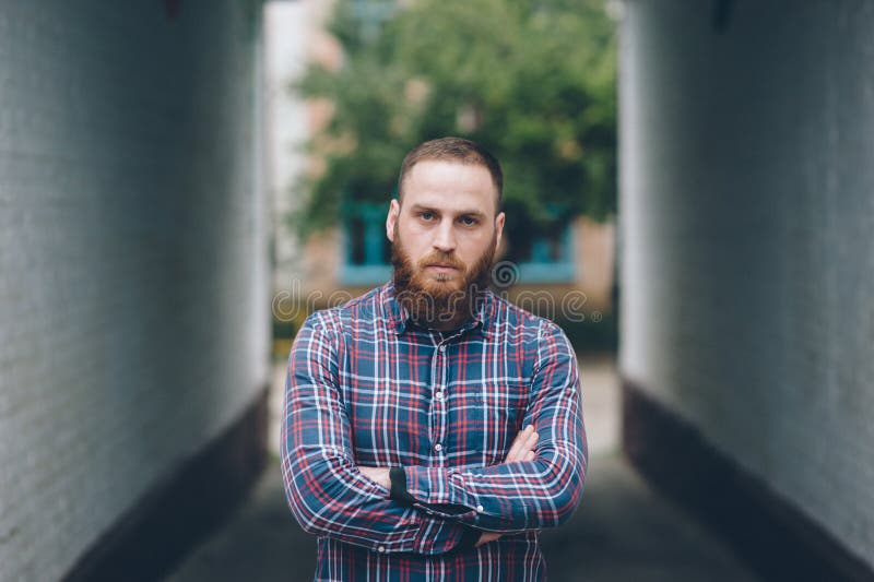 Handsome man with a beard in a flannel shirt standing on the street. Handsome man with a beard in a flannel shirt standing on the street