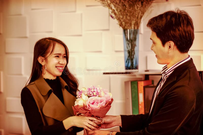 O homem considerável envia um sorriso ao ramalhete congratulatório das rosas, dá a uma menina um amante feliz, estilo do vintage foto de stock royalty free O homem considerável envia um sorriso ao ramalhete congratulatório das rosas, dá a uma menina um amante feliz, estilo do vintage foto de stock royalty free