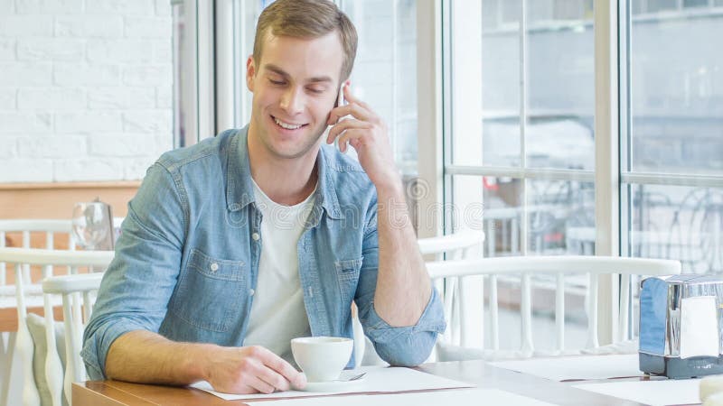 O homem considerável novo está tendo uma conversa do telefone