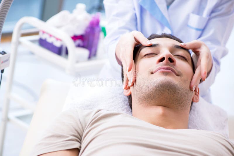 O homem considerável novo que visita o cosmetologist fêmea do doutor fotografia de stock royalty free O homem considerável novo que visita o cosmetologist fêmea do doutor fotografia de stock royalty free