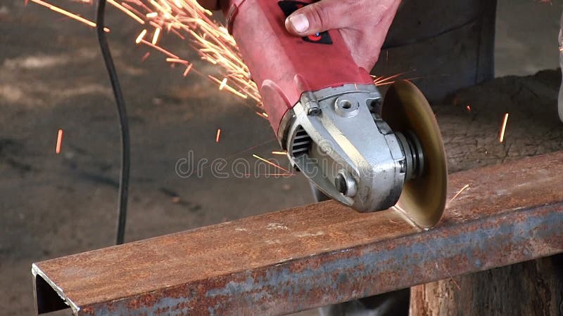 O homem corta um feixe oxidado do metal, usando uma turbina circular O close-up slowmotion do moedor de ângulo tem o som