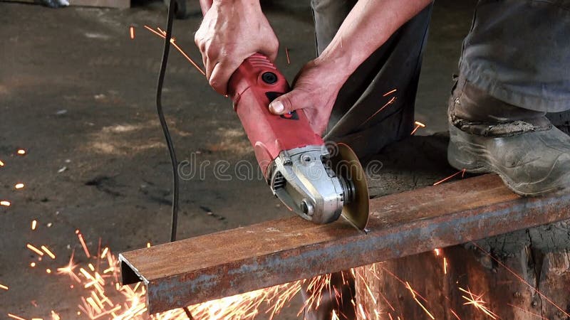 O homem corta um feixe oxidado do metal, usando uma turbina circular O moedor de ângulo slowmotion tem o áudio sadio