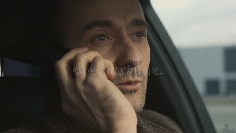 O homem de negócio bem sucedido fala pelo telefone que senta-se no close up do carro