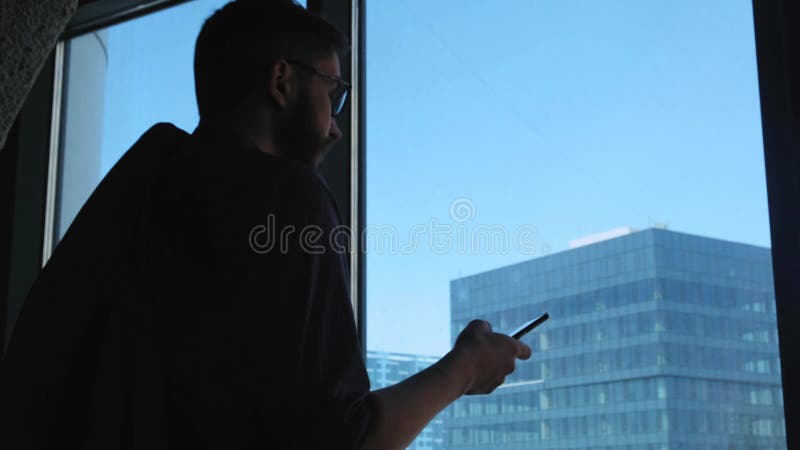 O homem de negócios bem sucedido novo põe sobre um revestimento sobre um fundo de uma janela com um tipo em uma baixa Negócio alt