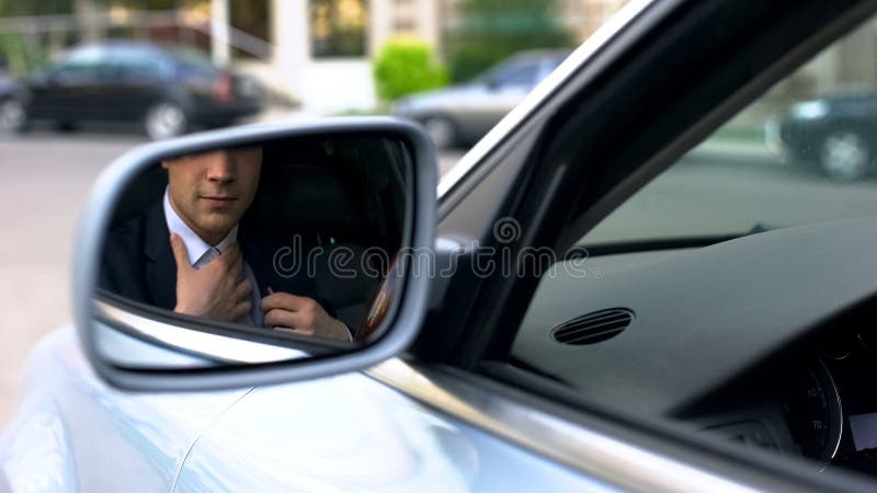 O homem de negócios que endireita a camisa, apronta-se encontrando-se, reflexão no espelho de asa imagens de stock royalty free O homem de negócios que endireita a camisa, apronta-se encontrando-se, reflexão no espelho de asa imagens de stock royalty free