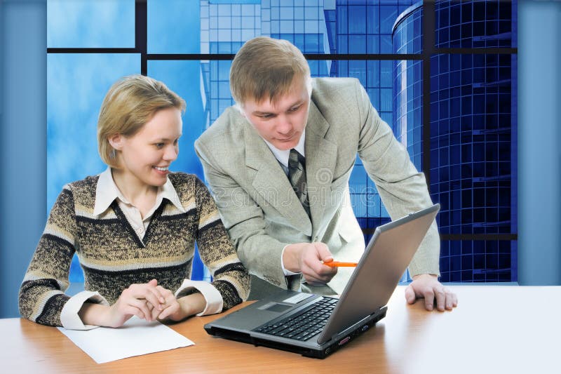 O homem e a mulher da equipe do negócio trabalham no escritório no portátil com edifícios do negócio da vista imagem de stock O homem e a mulher da equipe do negócio trabalham no escritório no portátil com edifícios do negócio da vista imagem de stock
