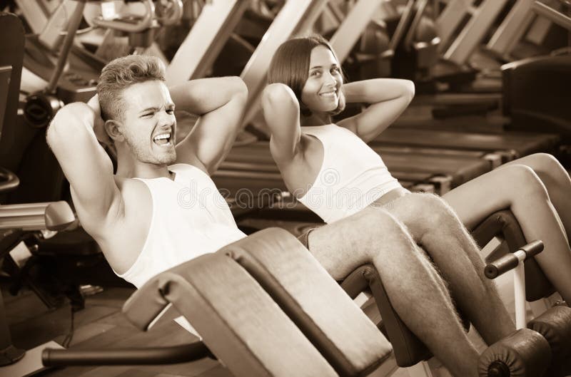 O homem e a mulher que fazem o Abs exercitam no gym fotos de stock O homem e a mulher que fazem o Abs exercitam no gym fotos de stock