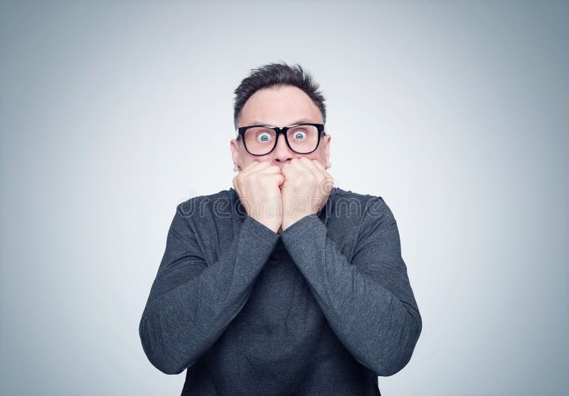 O homem em um t-shirt preto e em vidros é muito assustado Emoção profunda do conceito do medo foto de stock O homem em um t-shirt preto e em vidros é muito assustado Emoção profunda do conceito do medo foto de stock