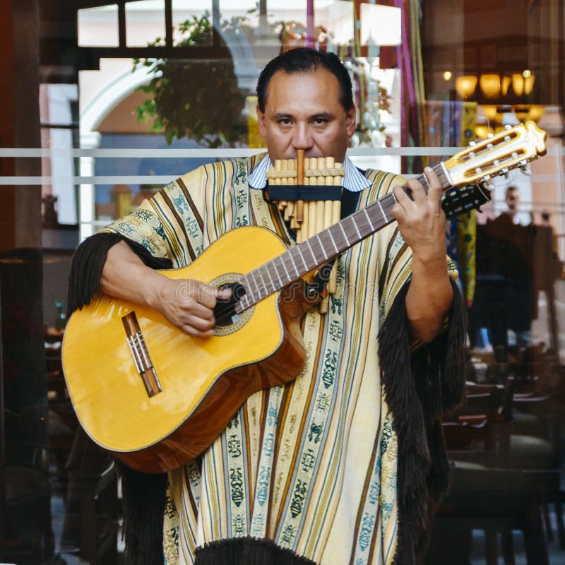O homem equatoriano local joga a guitarra e a flauta na rua imagens de stock O homem equatoriano local joga a guitarra e a flauta na rua imagens de stock