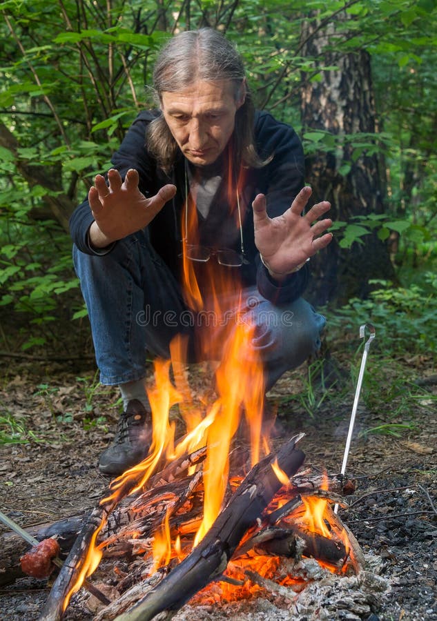 Man is warming his hands at the fire in the forest. Man is warming his hands at the fire in the forest