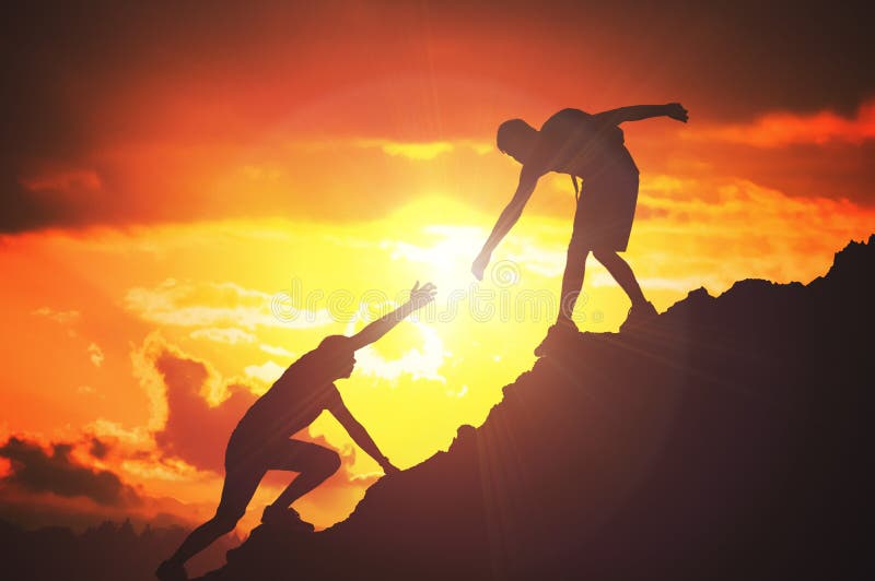 O homem está dando a mão amiga Silhuetas dos povos que escalam na montanha no por do sol foto de stock O homem está dando a mão amiga Silhuetas dos povos que escalam na montanha no por do sol foto de stock