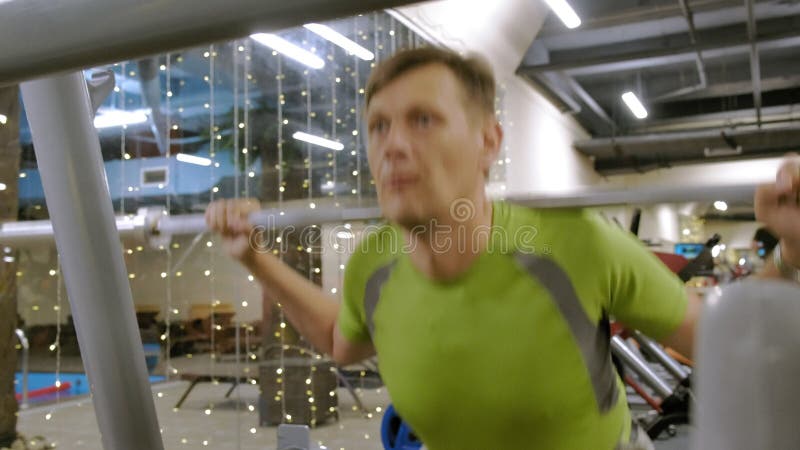 O homem excesso de peso faz ocupas com ocupas com um disco do peso para um barbell Homem da aptid?o training Conceito saud?vel do filme O homem excesso de peso faz ocupas com ocupas com um disco do peso para um barbell Homem da aptid?o training Conceito saud?vel do filme