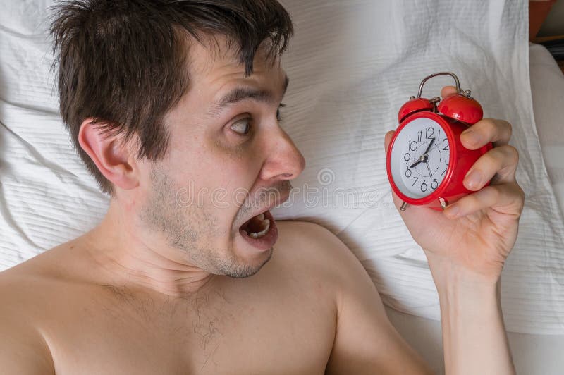 O homem frustrante e forçado novo está atrasado É acordar, olhando o despertador imagens de stock O homem frustrante e forçado novo está atrasado É acordar, olhando o despertador imagens de stock