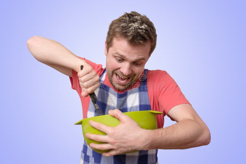 O homem guarda o kitchenware que cozinha com cara curiosa imagem de stock O homem guarda o kitchenware que cozinha com cara curiosa imagem de stock